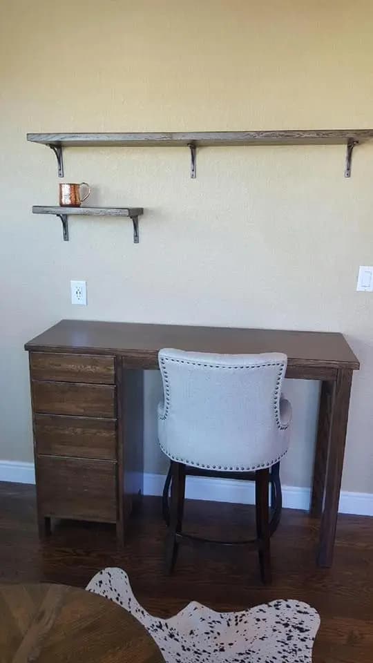 a desk with a chair and a shelf on the wall