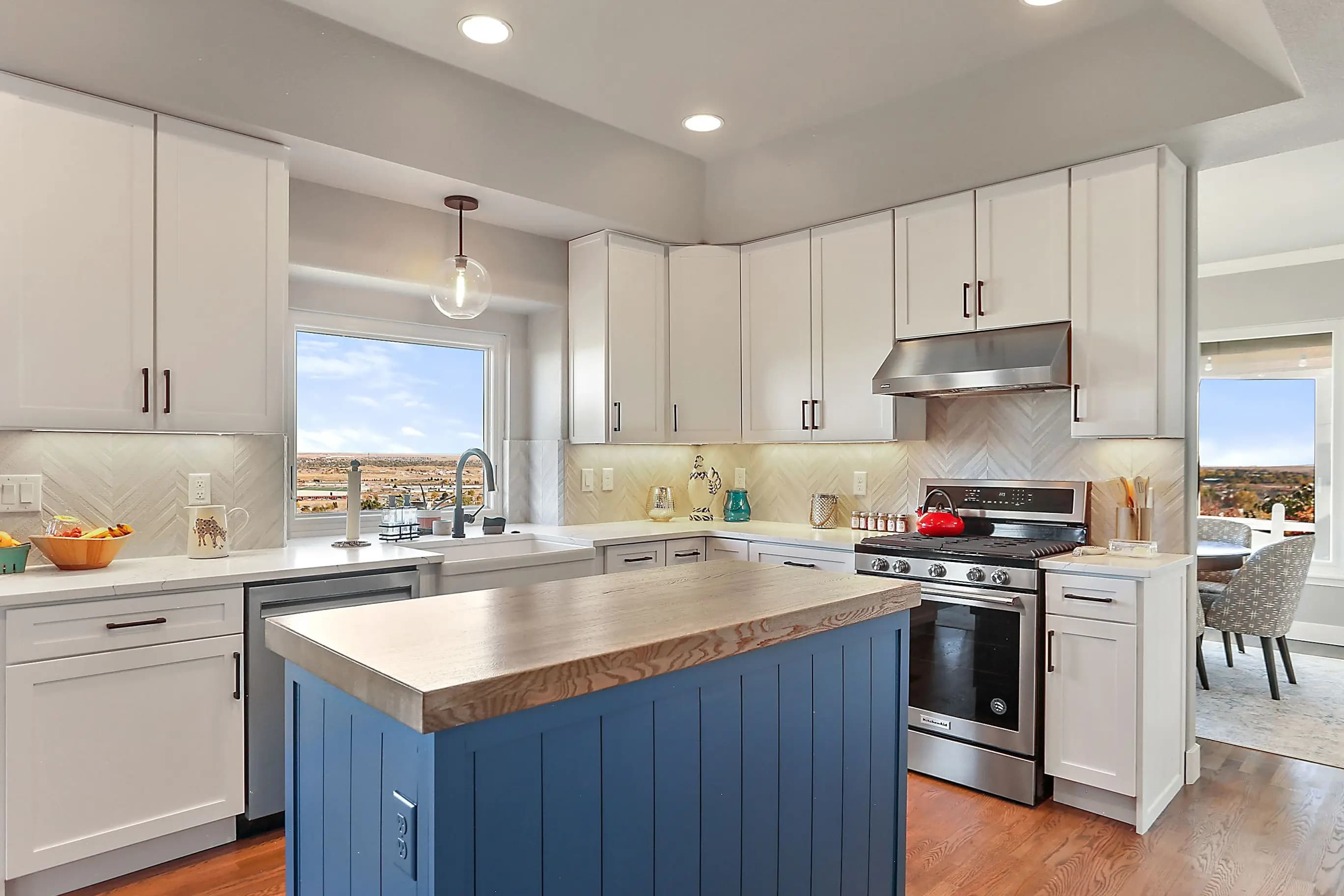 a kitchen with white cabinets and blue island