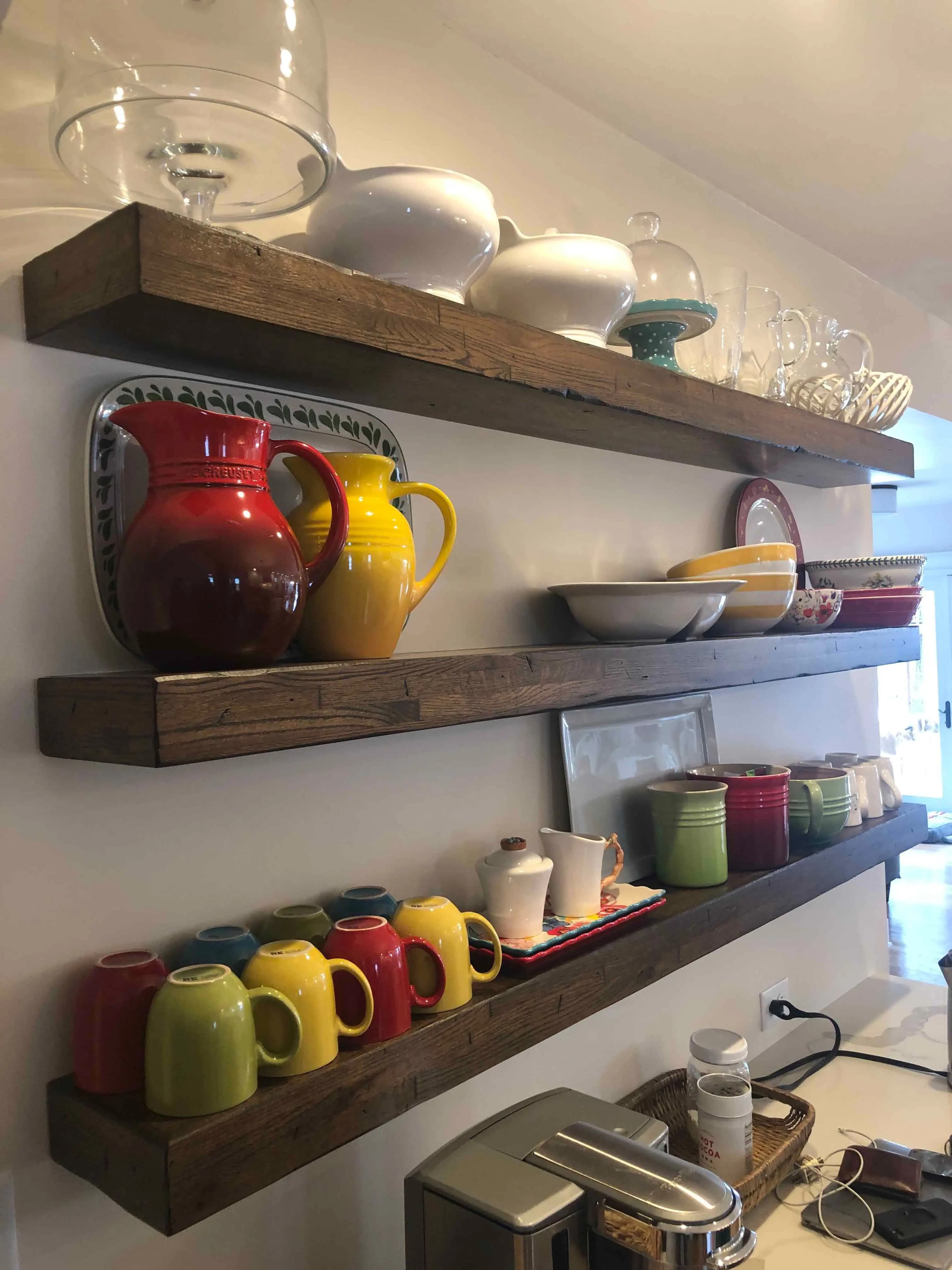 a shelf with different mugs ang vase on it